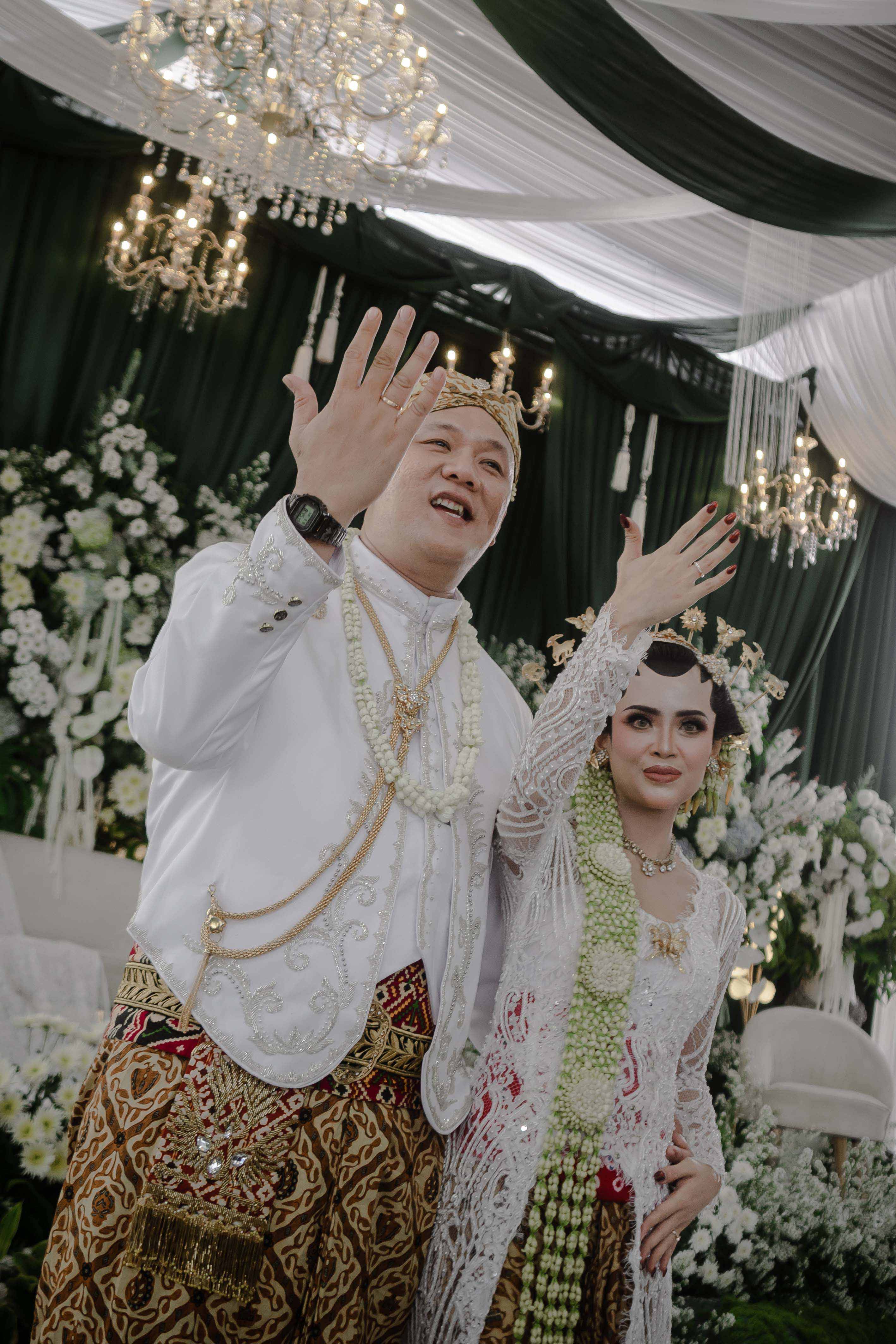 Pengantin mengenakan busana tradisional dalam suasana pernikahan